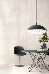 Modern dining area with a black pendant light, table, and chair against a seamless large porcelain panel wall.